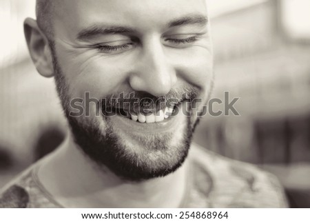 Shot of a handsome smiling young man with beard and blue eyes/Attractive man in urban city background