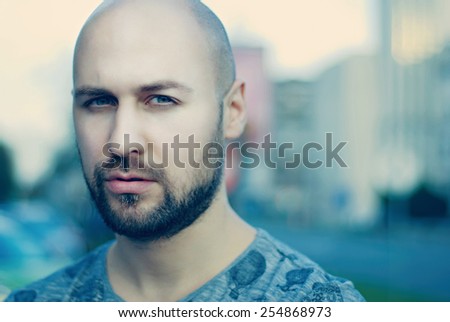 Shot of a handsome young man with beard and green eyes/Attractive man in urban city background