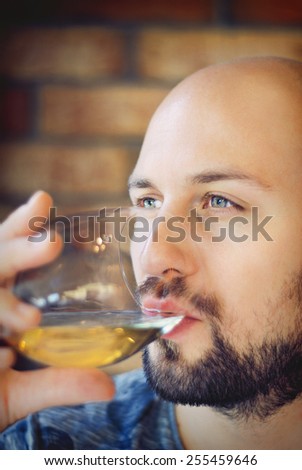 Shot of a handsome young man with beard and green eyes drinking wine in restaurant/Attractive man in restaurant