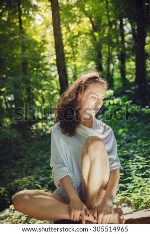 Yoga woman in white cloth meditating in beautiful green forest/Young woman practicing yoga in nature