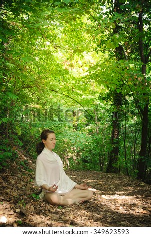 Yoga woman in white cloth practicing yoga in beautiful green forest/Young woman practicing yoga in nature