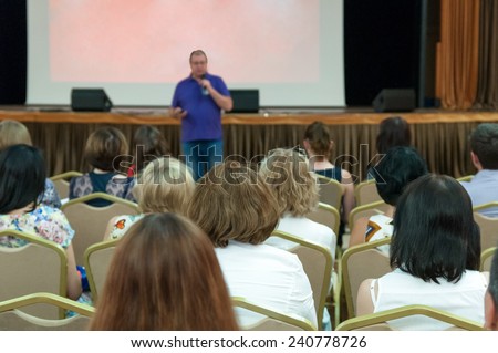 business conference - people sitting rare and speaker near the screen
