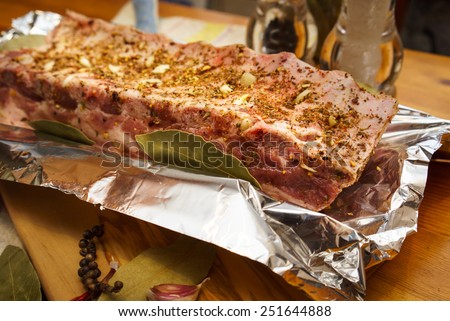 Fresh pork ribs, meat marinated and prepared for roast with garlic. Laying on a foil.