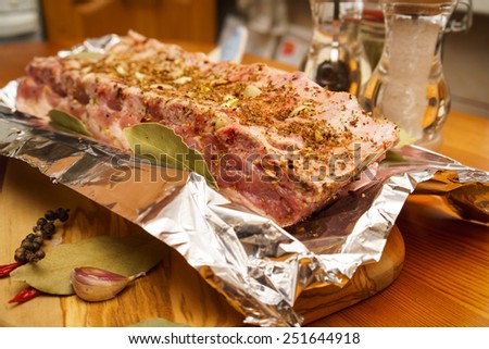 Fresh pork ribs, meat marinated and prepared for roast with garlic in a foil