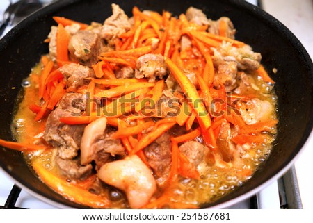 Restaurant cooking meat with carrot in frying pan
