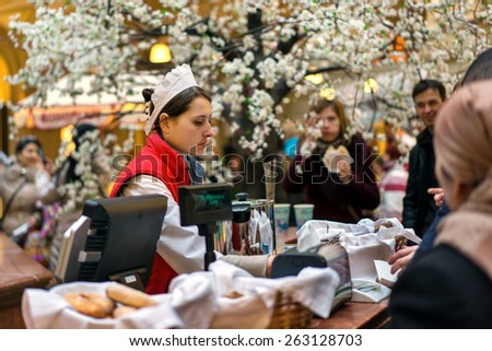 MOSCOW - MARCH 22: A buyer choosing a baking in the GUM store on March 22, 2015 in Moscow. GUM is the large store facing Red Square. It is popular among international tourists.
