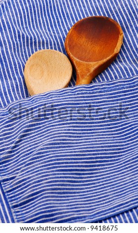 two wooden spoons in pocket of blue and white apron
