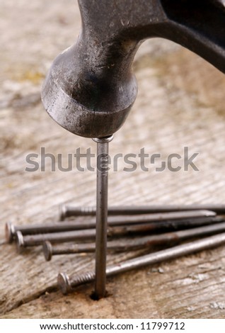 hammer and nails with focus on hammer hitting head of nail.  Depth of field meant to soften focus on background to make hammer and nail stand out