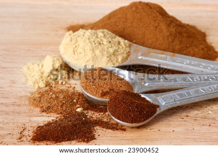Spices in measuring spoons on a wooden cutting board