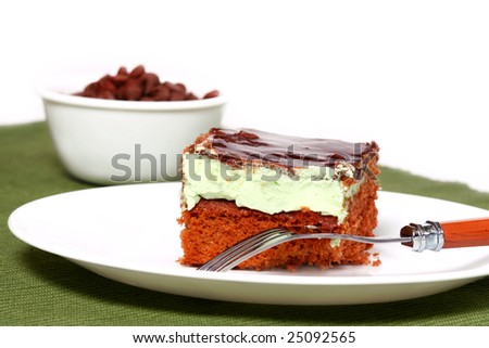 Piece of chocolate mint layered cake with bowl of chocolate chips