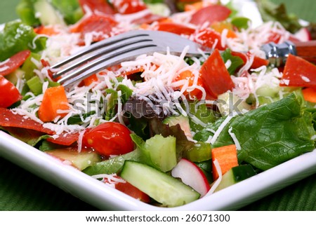 Close up of a delicious green salad full of vegetables with a fork