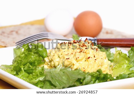 Egg salad on romaine lettuce with eggs in the background