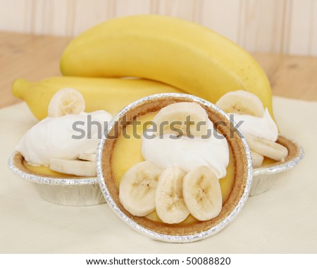 Three mini banana pudding pies with banana slices and whipped topping