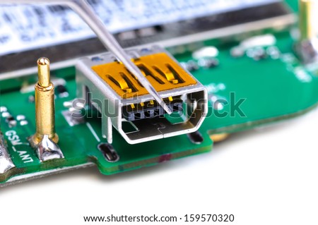 Electronic technician repairs mini USB socket on mobile phone circuit board. Close-up with selective focus and Shallow Depth of Field. Isolated on white background.