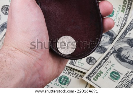 Man hand holds old purse with one quarter coin against background of hundred dollars banknotes.