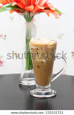 Glass of ice coffee and milk with fabric flower in glass vase