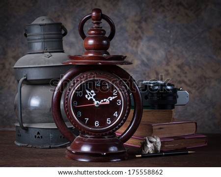 Group of objects on wood table. old clock, old rusty kerosene lamp ,old books , pencil, old camera, Still life