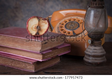 Group of objects on wood table. Dry rot apple, old rusty kerosene lamp, old book, old telephone , Knowledge concept