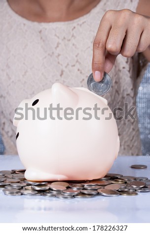 Woman hand inserting a coin into a piggy bank