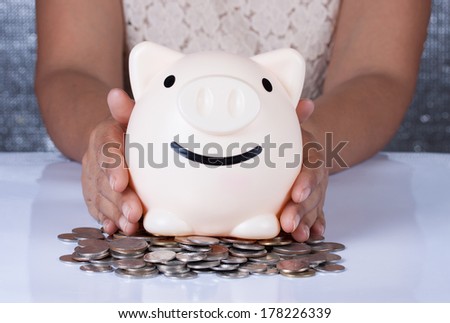 Woman hand inserting a coin into a piggy bank