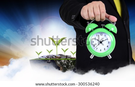 businessman holding clock on abstract background with money concept,(Elements of this image furnished by NASA)