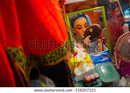 TALAD-NOI, THAILAND - OCT 06, 2013: A Chinese Opera actress applies makeup backstage before her show at the TALAD-NOI vegetarian cafeteria celebrating the Nine Emperor Gods Festival in Thailand.