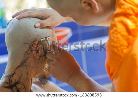 NONTHABURI, THAILAND - APRIL 08 : Thai man gets his head shaved by a monk during a Buddhist ordination ceremony on April 08, 2013 in Nonthaburi, Thailand.