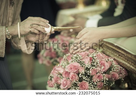 hand of a bride and groom receiving holy water from elders in thai culture wedding ceremony