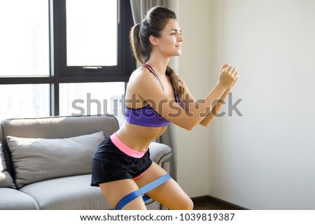 Beautiful woman during her home workout with a rubber resistance band
