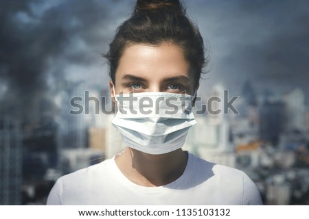 Air pollution in the city. Woman wearing face mask for protection.
