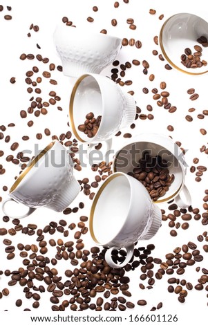 Falling coffee cups and beans over white background