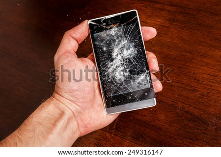 Smartphone with cracked display in hand