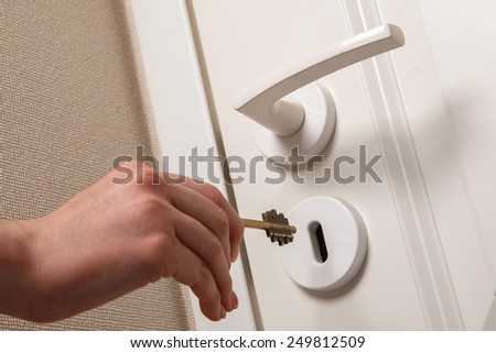 Hand with key beside the door
