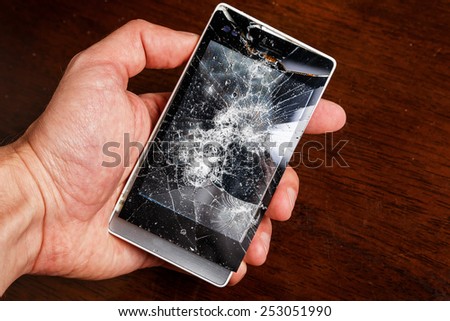 Smartphone with cracked display in hand