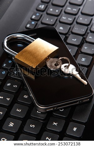 Smartphone and padlock is lying on a laptop keyboard