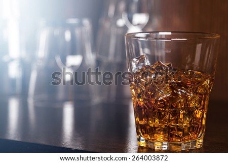 Glasses with whiskey on wooden bar counter and optical flare effect