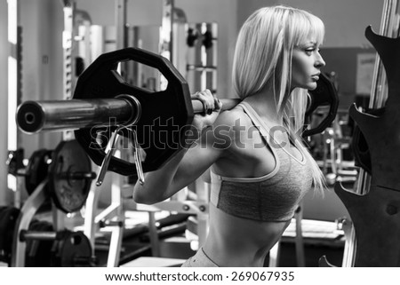 Young and beautiful woman with barbell on her shoulders