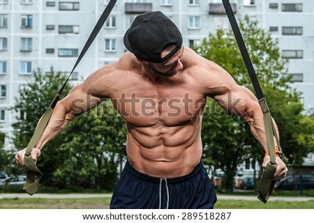 Man during workout with suspension straps on the street