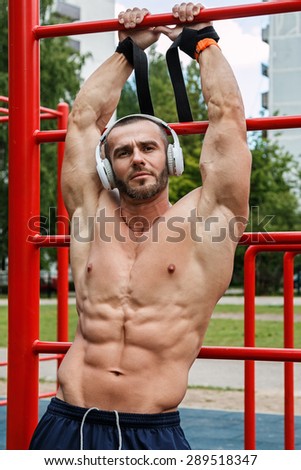 Muscular man listening music  during his street workout