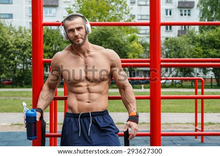 Muscular man listening music  during his street workout