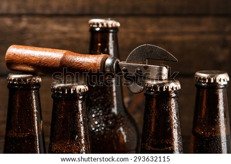 Bottles with beer and vintage opener over wooden background