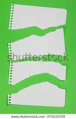 Torn pieces of checkered paper on green background