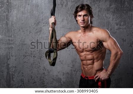 Muscular man during workout with suspension straps