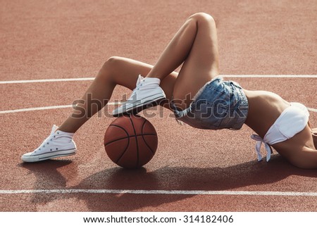 Young and sexy girl is lying on the basketball ground