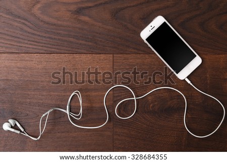 Smart phone and earphones on wooden surface