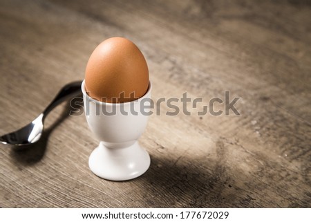 Soft Boiled Egg in a White Egg Stand with Spoon on a Rustic Wood Background