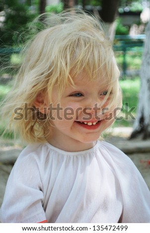 In the summer, a little girl on the street blonde smiling