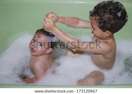 Brother and little sister bathed in a bubble bath.