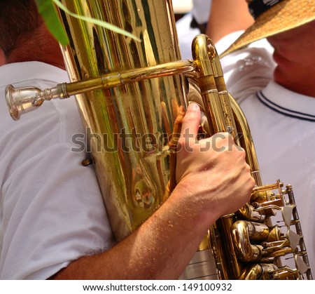 Musician of a musical band carrying the bright tuba with his hands, brass wind instrument