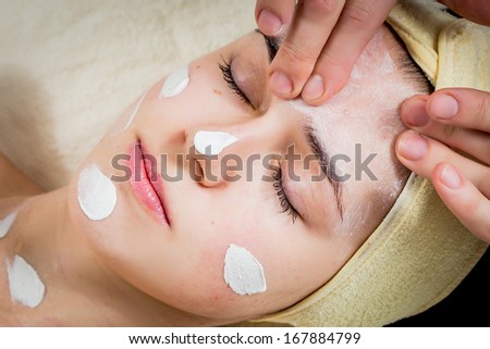 Cosmetologist apply cream to face of woman